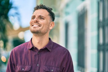 Genç İspanyol adam gülümseyerek şehirde mutlu mesut dikiliyor..