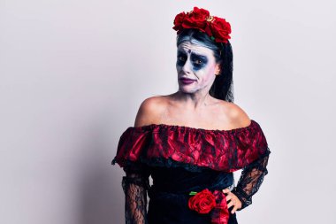 Ölü makyajcı, şüpheci ve gergin Meksika günü kıyafeti giyen genç bir kadın sorun yüzünden surat asıyor. negatif kişi. 