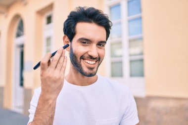 Genç İspanyol adam gülümsüyor. Şehirdeki akıllı telefonu kullanarak mutlu bir sesli mesaj dinliyor..