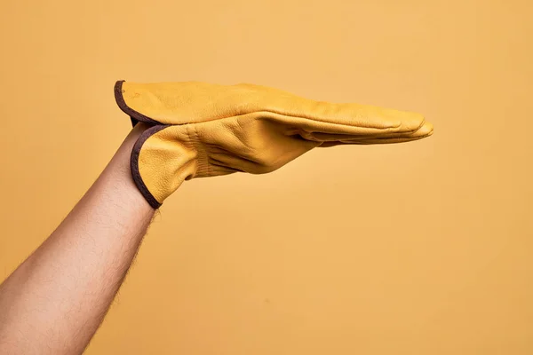 Mão Homem Jovem Caucasiano Com Luva Jardineiro Sobre Fundo Amarelo — Fotografia de Stock