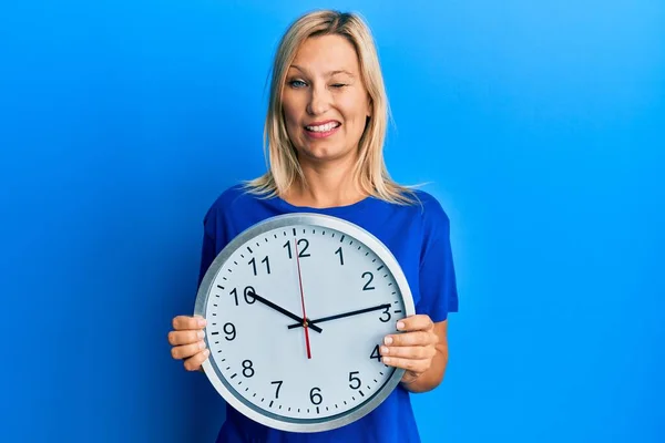 Hermosa Mujer Rubia Mediana Edad Sosteniendo Gran Reloj Guiñando Ojo — Foto de Stock