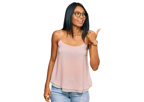 若いアフリカ系アメリカ人女性を着てカジュアルな服と幸せな顔を見て笑顔と親指で側を指してアップ — ストック写真