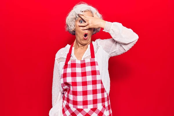 Senior Grey Haired Woman Wearing Apron Peeking Shock Covering Face — 스톡 사진