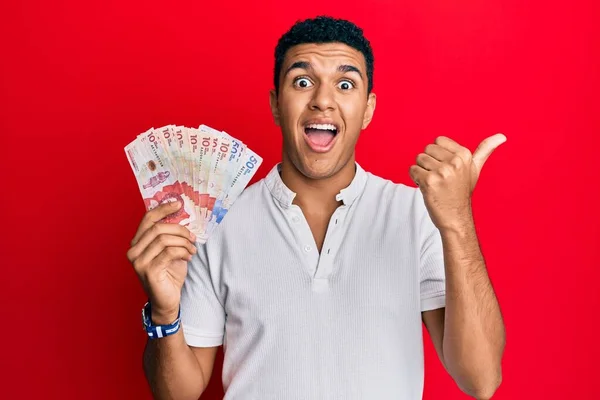 Young Arab Man Holding Colombian Pesos Pointing Thumb Side Smiling — Stock Photo, Image