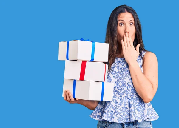 Young Beautiful Brunette Woman Holding Birthday Gift Covering Mouth Hand — Stock Photo, Image