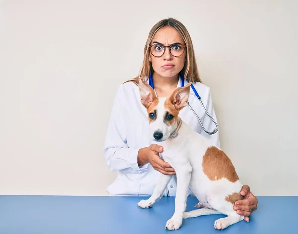 年轻美丽的金发碧眼的兽医妇女检查狗的健康怀疑和紧张 皱着眉头因问题而烦恼 消极的人 — 图库照片