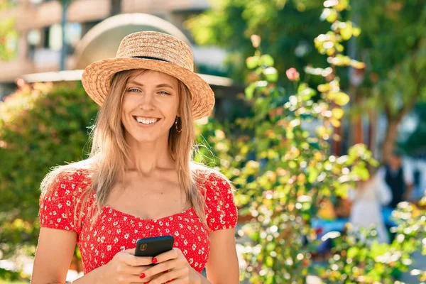 公園でスマートフォンを使用して夏のスタイルを身に着けている若いブロンドの観光女性 — ストック写真
