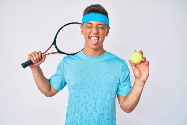 若いですヒスパニック男の子プレイテニスホールディングラケットとボールステッキング舌アウト幸せとともに面白い式 — ストック写真