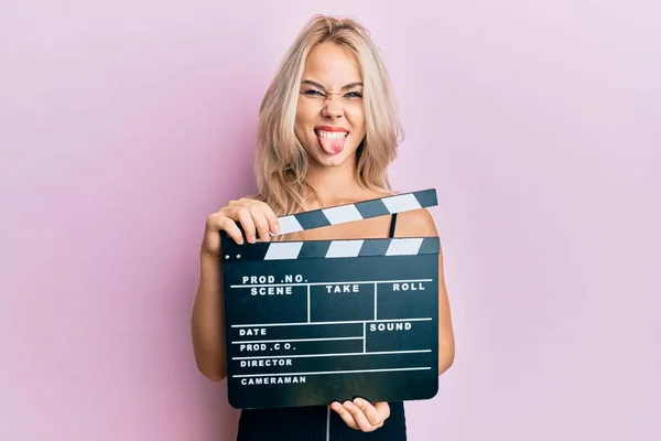 Beautiful Caucasian Blonde Girl Holding Video Film Clapboard Sticking Tongue — Stock Photo, Image