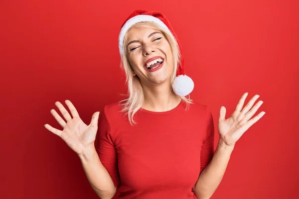 Mladá Blondýnka Vánočním Klobouku Oslavuje Šílenost Šílenství Úspěchu Zdviženýma Rukama — Stock fotografie