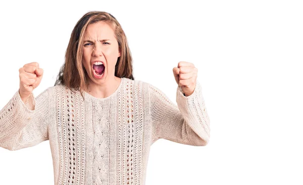 怒って怒っているカジュアルなセーターを着て若い美しいブロンドの女性と怒りで叫んでいる間に怒りと怒りの拳を上げる 怒りと攻撃的な考え方 — ストック写真