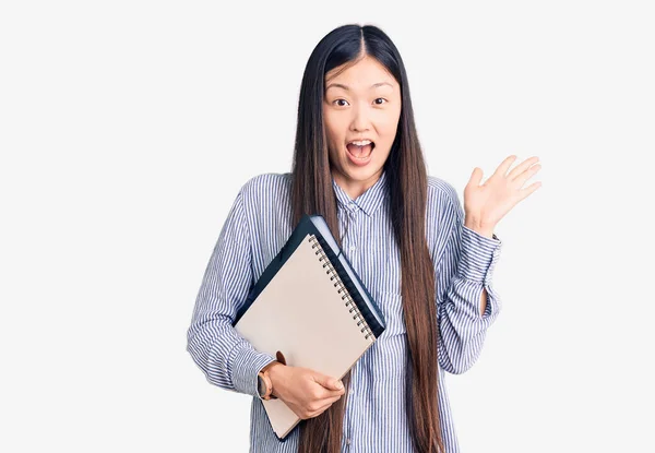 Joven Mujer China Hermosa Sosteniendo Cuaderno Celebrando Victoria Con Sonrisa —  Fotos de Stock