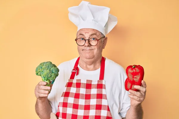 남자가 요리사 앞치마를 브로콜리를 고추는 모르고 스러운 표정을 있습니다 — 스톡 사진