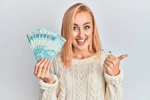 Krásná Kavkazská Blondýnka Drží 100 Brazilských Reálných Bankovek Ukazující Palcem — Stock fotografie