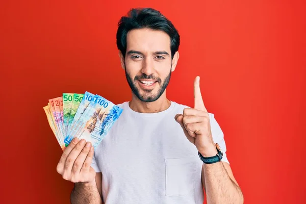 Joven Hispano Sosteniendo Billetes Banco Suizos Sonriendo Con Una Idea —  Fotos de Stock