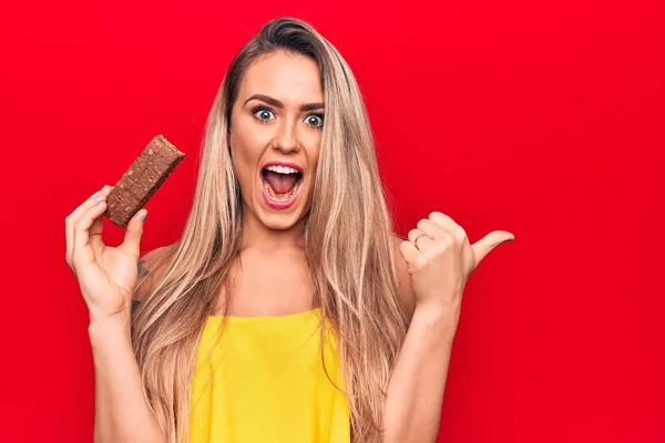 Jovem Mulher Loira Bonita Comendo Barra Proteína Chocolate Sobre Fundo — Fotografia de Stock