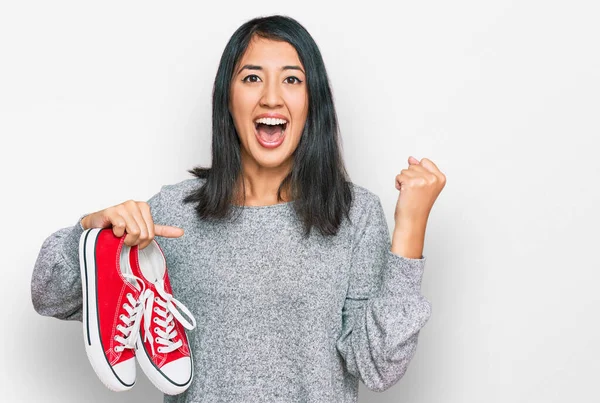 Hermosa Mujer Joven Asiática Sosteniendo Zapatos Casuales Rojos Gritando Orgulloso —  Fotos de Stock