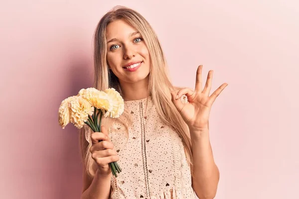 Mladá Blondýnka Drží Květiny Dělá Znamení Prsty Usmívá Přátelské Gestikulace — Stock fotografie