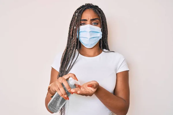 Νεαρή Αφροαμερικανή Γυναίκα Κοτσίδες Που Φοράει Ιατρική Μάσκα Χρησιμοποιώντας Απολυμαντικό — Φωτογραφία Αρχείου