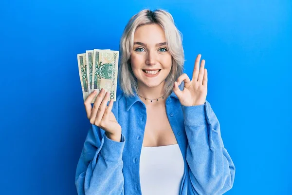 Young Blonde Girl Holding Polish Zloty Banknotes Doing Sign Fingers — Stock Photo, Image