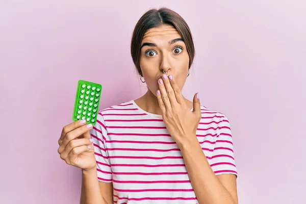 Młoda Latynoska Trzymająca Tabletki Antykoncepcyjne Zakrywające Usta Dłonią Zszokowana Bojąca — Zdjęcie stockowe