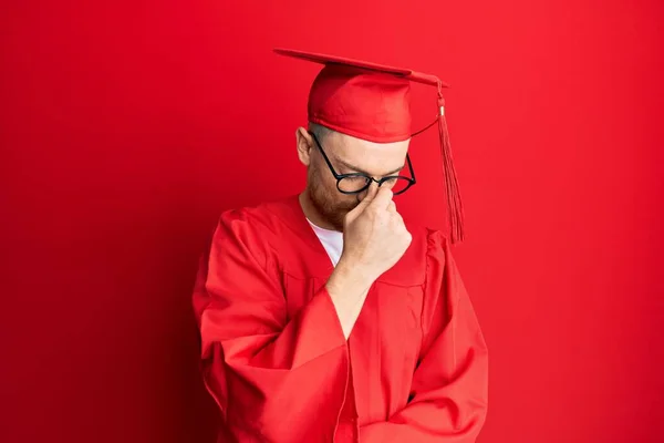 Νεαρός Κοκκινομάλλης Κόκκινο Καπέλο Αποφοίτησης Και Επίσημη Ρόμπα Κουρασμένος Τρίψιμο — Φωτογραφία Αρχείου