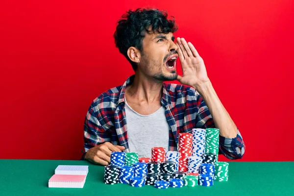 Jovem Hispânico Sentado Mesa Com Fichas Poker Cartas Gritando Gritando — Fotografia de Stock