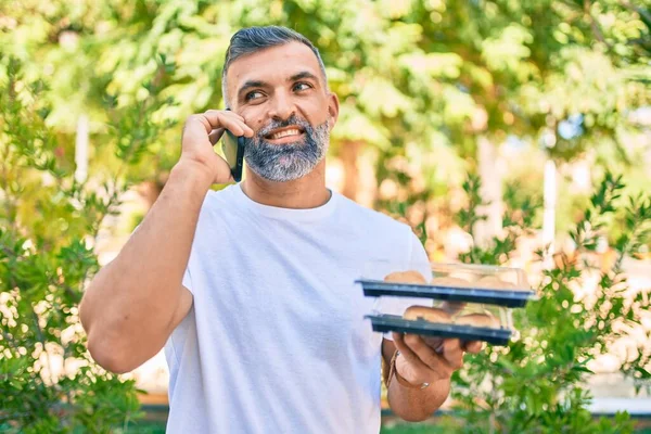 Hombre Pelo Gris Mediana Edad Hablando Teléfono Inteligente Sosteniendo Comida —  Fotos de Stock