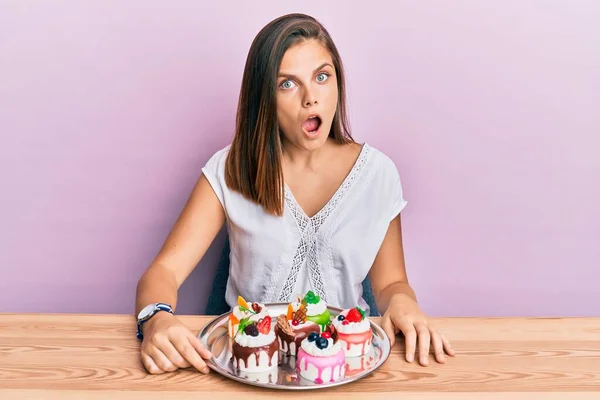 若いです白人女性食べるペストリーのための朝食怖がってと驚きのために口を開けて驚いて 不信顔 — ストック写真