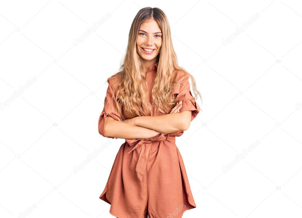 Beautiful caucasian woman with blonde hair wearing summer jumpsuit happy face smiling with crossed arms looking at the camera. positive person. 