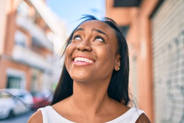 Genç Afrikalı Amerikalı kadın gülümseyerek şehirde mutlu mesut yürüyor..