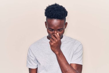 Genç Afro-Amerikan adam günlük kıyafetler giyip yorgun burnu ve gözleri ovuşturup yorgun ve baş ağrısı çekiyor. Stres ve hüsran kavramı. 