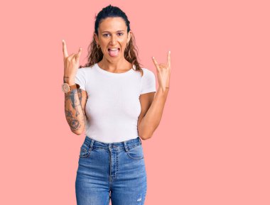 Dövmeli, beyaz tişörtlü, çılgın bir ifadeyle bağıran, elleri havada rock sembolü yapan genç İspanyol bir kadın. Müzik yıldızı. ağır müzik konsepti. 