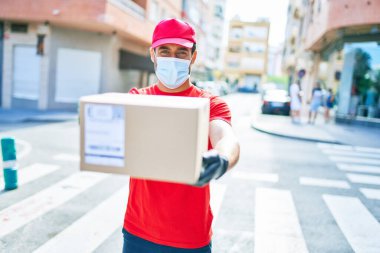 Genç teslimatçı üniforma ve koronavirüs koruma maskesi takıyor..