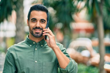 Genç İspanyol adam gülümsüyor. Şehirdeki akıllı telefondan konuşuyor..