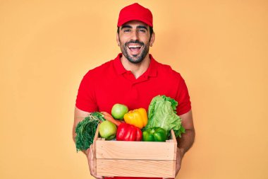 Yakışıklı, sakallı, üniformalı, teslimat yemeği taşıyan ve kahkahalarla gülen bir adam.. 