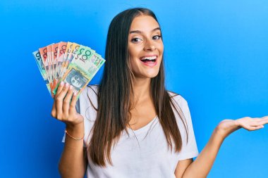 Avustralya doları tutan genç İspanyol kadın başarıyı mutlu bir gülümsemeyle kutluyor ve kazanan el kaldırarak ifade ediyor 