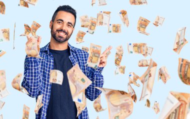 Gündelik kıyafetler giyen, kendine güvenen, parmaklarını farklı yönlere çeviren genç İspanyol adam. reklam için kopyalama alanı