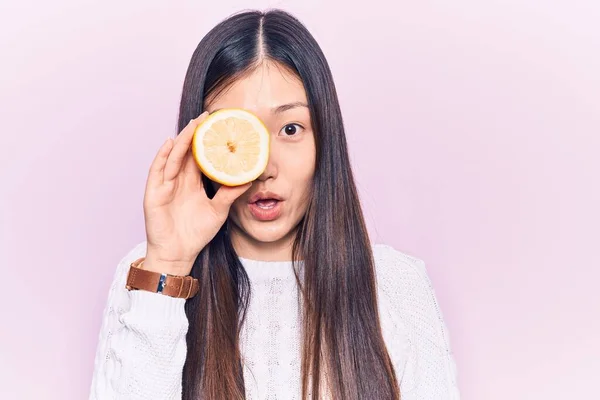 Молодая Красивая Китаянка Держит Кусочек Лимона Над Глазом Испуганный Удивленный — стоковое фото