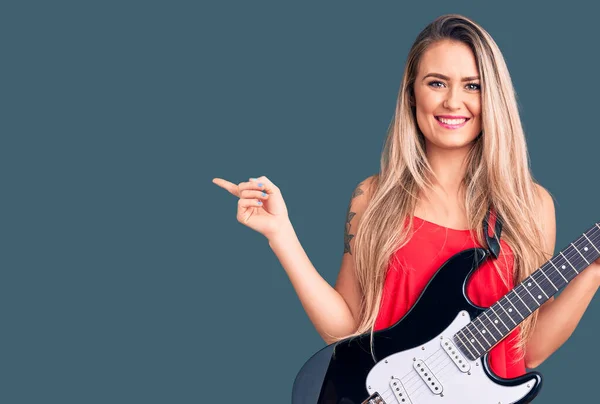 Jovem Bela Mulher Loira Tocando Guitarra Elétrica Sorrindo Feliz Apontando — Fotografia de Stock