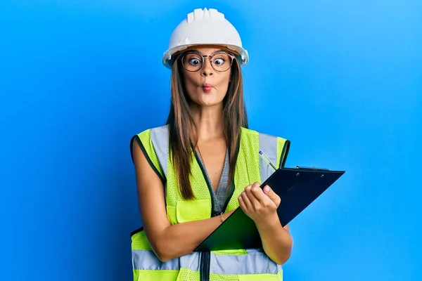 Jonge Spaanse Vrouw Draagt Veiligheidshelm Met Klembord Vissengezicht Met Mond — Stockfoto