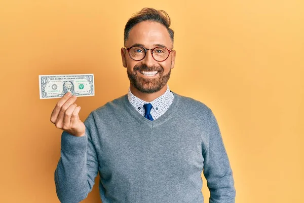ハンサムな中年男性保持1ドル紙幣見て正と幸せな立ちと笑顔で自信を持って笑顔ショー歯 — ストック写真