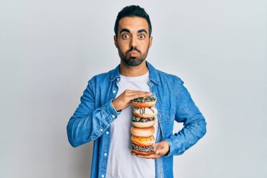 Lezzetli donutlar tutan genç İspanyol adam komik yüzlü yanakları şişiriyor. Ağzı havayla şişer, havayı yakalar.. 