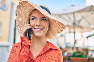 Genç, sarışın, gülümseyen, mutlu, akıllı telefondan konuşan bir kadın..