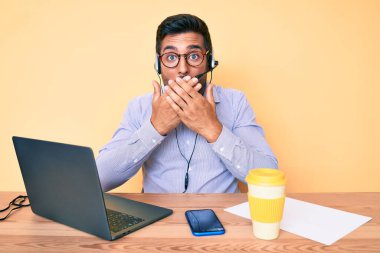 Çağrı merkezindeki operatör kulaklığı takan İspanyol genç adam yanlışlıkla ağzını kapatırken şok oldu. gizli kavram. 