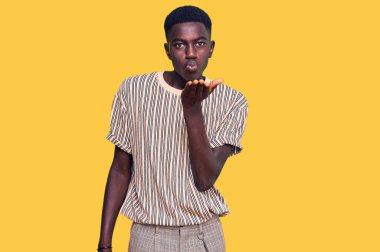 Gündelik giysiler giymiş genç Afro-Amerikan bir adam kameraya bakıp havada el ele öpüşerek sevimli ve seksi oluyor. aşk ifadesi. 