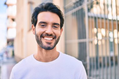Genç İspanyol adam gülümseyerek şehirde mutlu bir şekilde yürüyor..