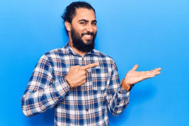 Gündelik giysiler giyen genç Arap adam kameraya hayret ediyor ve gülümsüyor.. 