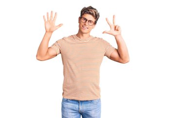 Genç yakışıklı adam, günlük kıyafetler ve gözlük takıyor. Sekiz numaralı parmaklarıyla gösteriyor ve işaret ediyor. Kendinden emin ve mutlu bir şekilde gülümsüyor.. 