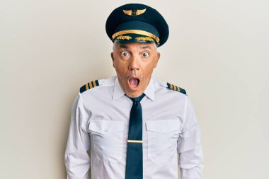 Yakışıklı, olgun, uçak pilotu üniforması giyen, şaşırmış ve şaşırmış bir ifadeyle korku ve heyecanlı bir yüz ifadesi olan bir adam.. 